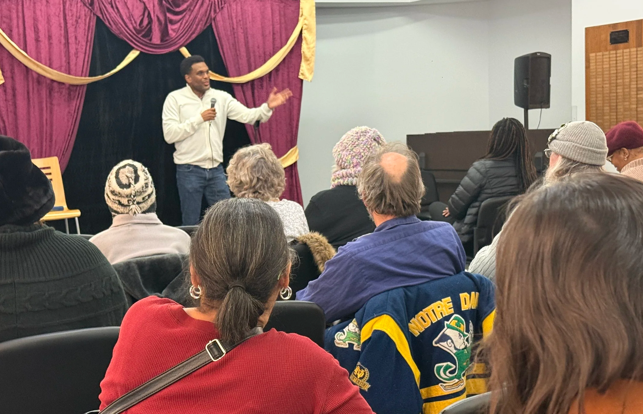 A comedian performing for a full house of adults in a library meeting room
